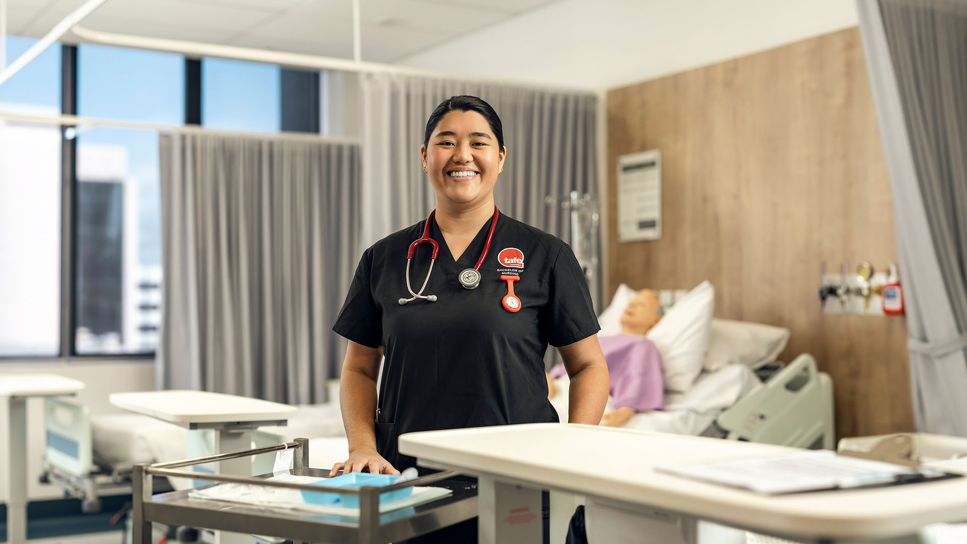 Irish, an Asian-Australian woman, stands in a TAFE Queensland nursing student uniform in a practical lab.
