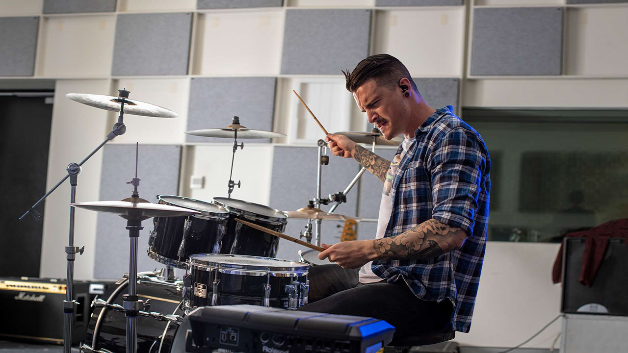 Photograph of student playing the drums in a TAFE Queensland music and recording studio